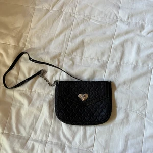 H&M Svart Väska - Svart väska från H&M som är hjärtmönstrad. Måttet på väskan är cirka 13x17 cm.