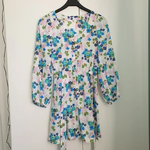 Retro klänning - Blommig kort klänning med söta rosa knappar och knytning runt midjan :). Köpt på Second Hand för flera år sedan men aldrig använd. Det står inget märke eller storlek så jag skulle gissa att den är hemsydd. Men jag skulle säga att den är storlek S ☺.