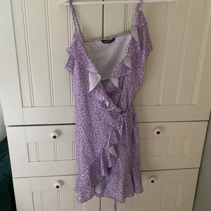Omlottklänning - Jättefin lila omlottklänning i småblommigt tyg.  Sparsamt använd, fint skick. Hör av dig vid intresse/ mer bilder.  Köpare står för frakt.