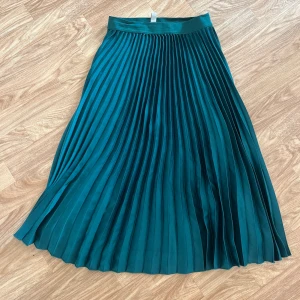 Grön Plisserad Kjol  - Säljer den här superfina kjolen från H&M då den tyvärr inte har kommit till så mycket användning. Den slutar strax under knäna på mig som är 175 cm och är använd vid endast ett fåtal gånger! 