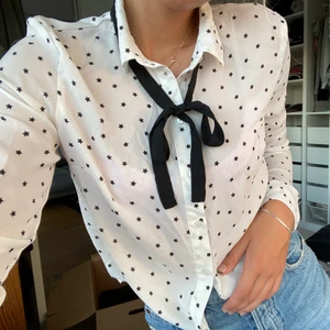 Skjorta - Jättesöt skjorta från hm i storlek 38. Lite liten i storleken. Skjortan är vit med svart stjärnor på. Det svarta bandet går att knyta o knyta upp själv, går även att ta av.💞