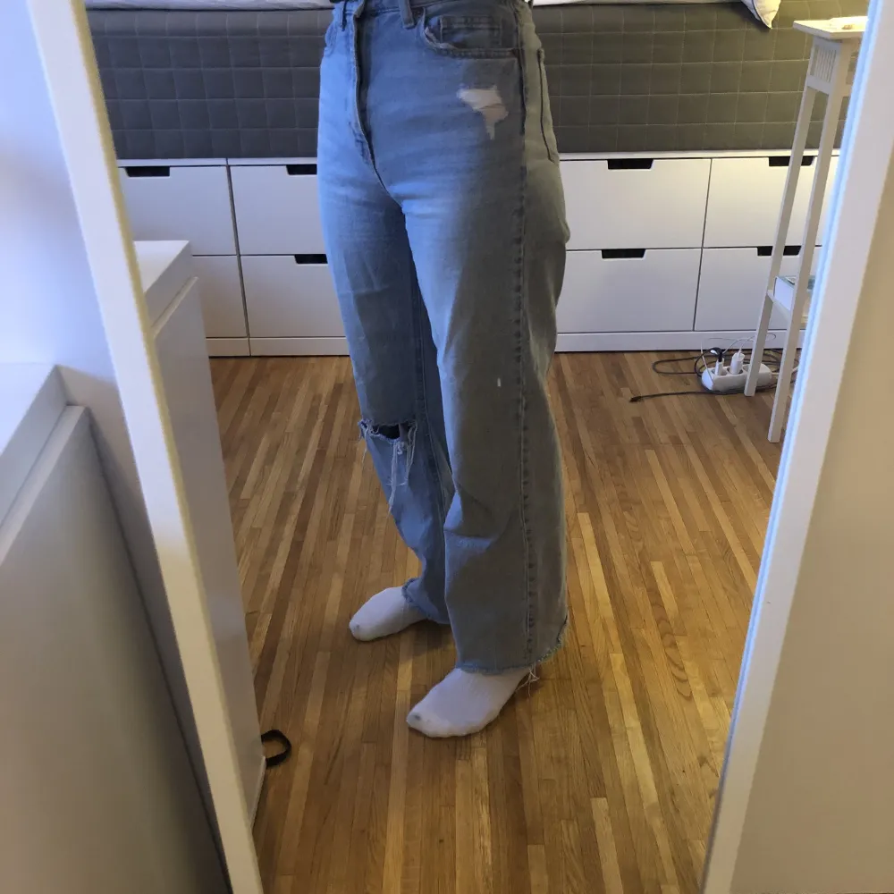 Högmidjade ljusblå jeans med hål från H&M. I ganska bra skick men hålet är lite slitet. Säljer eftersom att de inte passar min stil längre. . Jeans & Byxor.
