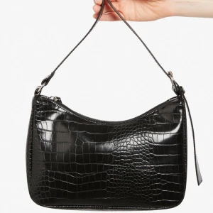 Axelremsväska  - Svart axelremsväska i faux croc från Monki. 90-talsstil. Aldrig använd.