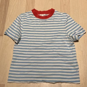 Tröja från COS - En blå/vitrandig tröja med röd krage. Perfekt till sommaren, säljs p.g.a att den var för liten