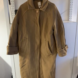 Ljusbrun kappa i ullmix  - Ljusbrun rock i ullblandning från H&M säljes. Gott men använt skick. Oversize i modellen och passar XS-M. 