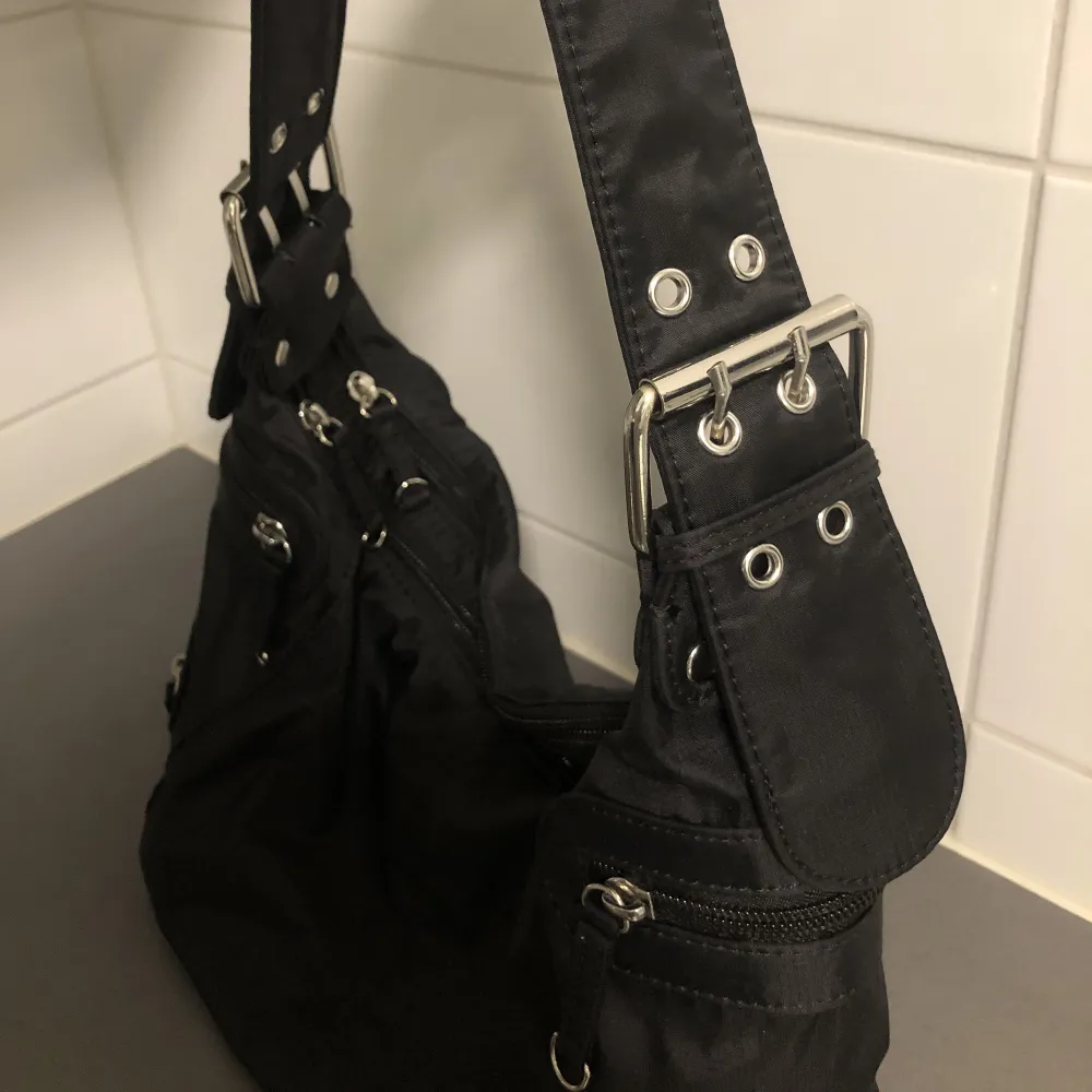 En medelstor hand/axelväska i svart med snygga silvriga detaljer 💥 i fint skick. Frakt 60 kr . Väskor.