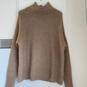 Stickad tröja - Jättemysig, varm stickad tröja. Oversized med polo. Lätt att klä upp och ned. Mycket bra skick. Färgen är en blandning av brun och beige.
