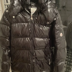 Moncler maya  - Moncler maya. Osäker på om den är äkta eller inte för jag köpte den av en kompis som säger att den är äkta(inte 100) på att den är äkta. På andra bild ser du en liten defekt men det är inget man tänker på när dragkedjan är uppe. Skriv om du har frågor.