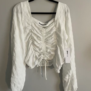 Helt ny topp, 38 - Vit festtopp från Gina Tricot med knyt fram och luftiga ärmar. Tyckte var fin och köpte, men har ej använt. Kostade 349:-. 