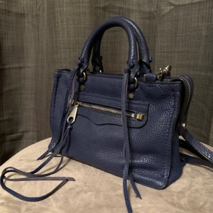 Oanvänd Rebecca Minkoff läderväska  - Säljer denna oanvända Rebecca minkoff väskan i marinblått läder. En väldigt rymlig väska som man både kan hålla i handen eller ha i axelbandet. Köpt för 3000kr, säljs därför oanvänd för 1800kr. (Medföljer en extra läderremsa som man själv kan fästa om någon annan skulle gå sönder) Hör av er vid frågor:) 