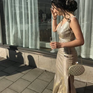 Balklänning - Säljer min balklänning jag använde i högstadiet. Köptes utomlands och har en sjukt finglittrig färg som skiftar från guld/rosé/silver. Den har en slit vid benet och ett tåg som e jättefint. Låg rygg, kan skicka fler bilder ifall det önskas😊 den är sydd efter mig men passade mig perfekt när jag var en liten 36/38. Jag är 167cm lång och den var perfekt längd med klackar. 