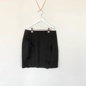 Svart kjol - En festlig svart fitted kjol med två volangdetaljer på framsidan. Aldrig använd därmed nyskick, det är storlek M dock skulle jag säga att den är lite små i storleken.   Passar till allt och går att styla upp och ner.