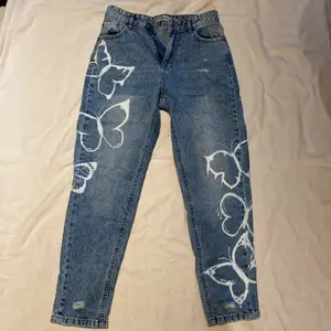Högmidjade jeans med slitningar och handmålade fjärilar. Byxorna är köpta på New yorker 