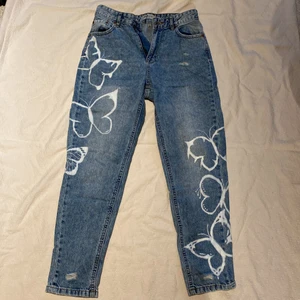Jeans med fjärils tryck strl S - Högmidjade jeans med slitningar och handmålade fjärilar. Byxorna är köpta på New yorker 