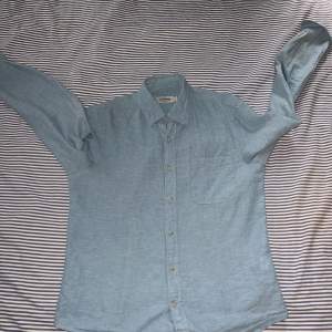 En ljusblå linneskjorta från Dressmann i storlek S
