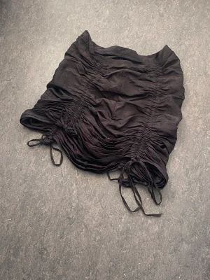 Draperad brun kjol - Kjol med 4 snören/draperingar. Kan bli kort eller medellång beroende på hur snörerna dras åt. Tyvärr för stor i midjan för mig. I gott skick