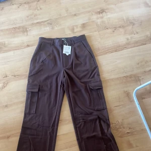 Cargobyxor - Chokladbruna cargobyxor i kostymmaterial aldrig använda då jag beställde för liten storlek därav finns prislappen kvar på byxorna 