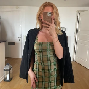 Rutig klänning från Pull&Beat - Tunn rutig klänning med breda axelband. Rolig att styla på olika sätt, funkar sommar som höst. 