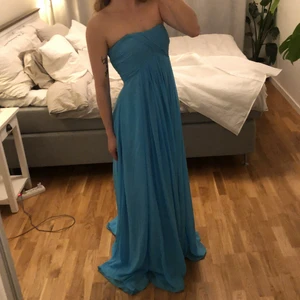 Ljusblå Balklänning - Sydd efter personliga mått men har storlek S/M och är 169 cm lång. Aningen tjockare tyg som bas och en ljust genomskinligt tyg utanpå. Klänningen är använd 1 gång på bal och är i väldigt bra skick. Enstaka smutsfläckar på det genomskinliga tygets nedersta del men annars ren. Beställdes via ”Light in the Box”. Mäter 90 cm runt bysten men någon med större omfång kan definitivt bära klänningen då den är aningen stor för mig i dagsläget.