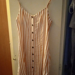 Somrig klänning  - Somrig och i super härligt tyg. Passar lika bra bara höngades som med en skärp runt. Passar dom flesta i storleken beroende på hur man vill ha den :) randig i vitt och rost färg 