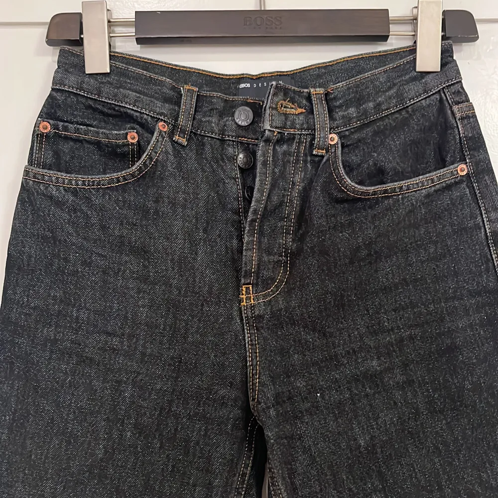 ASOS DESIGN mid rise '90's' straight leg jeans in vintage washed black. Använda 2-3 gånger och har inga skador, men passar tyvärr inte mig längre. Fem ficksmodell med knappar framtill och kopparfärgade sömmar.. Jeans & Byxor.