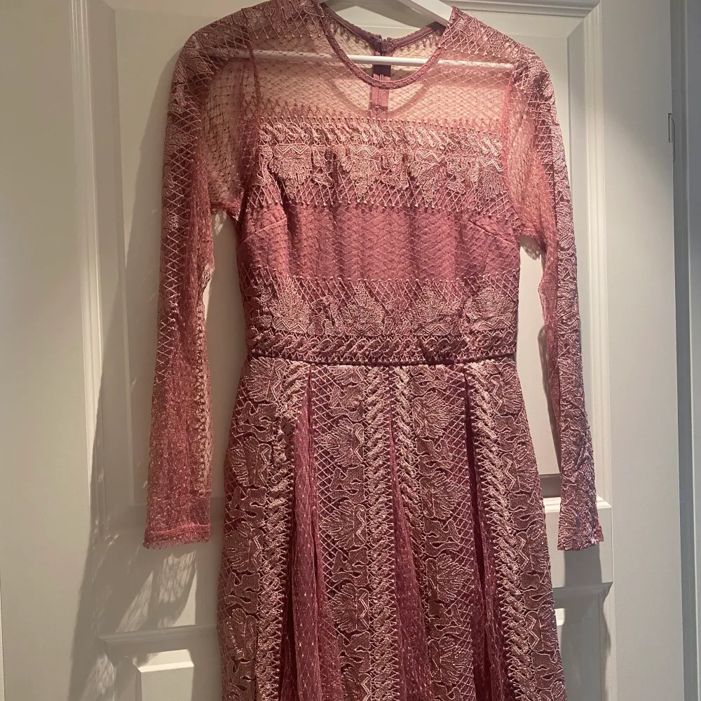 En rosa/lila långärmad klänning med ett fint mönster över hela klänningen. Den är endast använd 1 gång och är som ny. Klänningen är k storlek 36 med en bra passform. Pris kan diskuteras. . Klänningar.