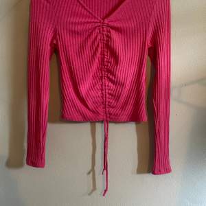 Denna rosa tröjan e tunn och ribbad tröja, man kan göra den mindre vid magen så de blir som en magtröja.
