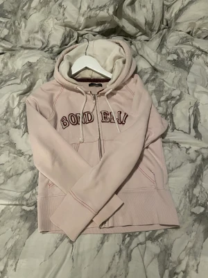 Bondelid hoodie - Ljusrosa bondelid hoodie. En kortare hoodie med dragkedja som slutar under naveln.