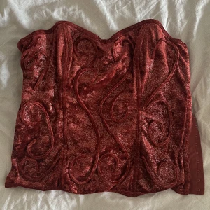 Glittrig korsettopp  - Jättessnygg korsett i sammetstyg! Tyget är lite skimrigt och den är i storleken 75B i bysten o skulle säga att den passar en S runtom!!