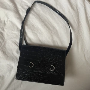 Svart Väska  - Svart väska i läder från Åhléns, oanvänd.  Banden går att justerar! 