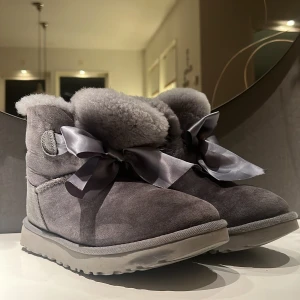 Uggs - Gråa Uggs med rosett! Skicket är ändå väldigt bra för att ha använt dom en hel höst/vinter/vår. Lite defekter som blir när det kommer blött på dom eftersom det är äkta. Köparen står för frakt, klicka inte på köp nu!❤️ nypris 2900. 