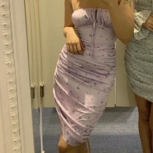 Adoore klänning - Klänning från Adoore, använd ca 3 gånger så den är i gott skick. Klänningen har ett justerbart snöre på sidan så man kan bestämma längd. Klänning säljs inte längre.