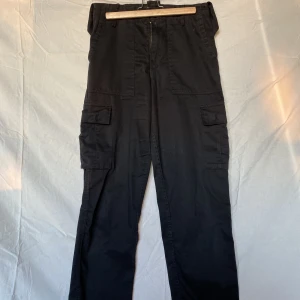 Kombat cargobyxor svarta - Väl använda svarta kombat cargo byxor. Otroligt sköna men väk använda! Saknar varsin knapp per ben men det går lätt att sy på hemma!