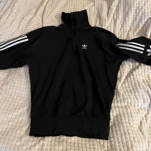 Adidas tröja - Använd få gånger, ny adidaslogga på ena armen, lång krage som går att vika ner, dragkedja vid halsen som går ner på bröstet ungefär, aningen stor i storleken 