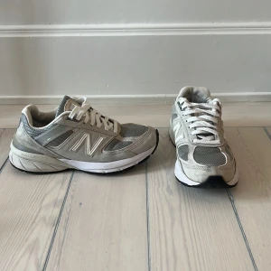 New Balance  - New Balance 990 sneakers  Använda med märkbart slitage men i gott skick.  Liten skada på höger skos insida (bild 2 och 3)  Storlek 36,5/37 Nypris ca 2500kr 