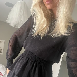 Svart mesh klänning - Jättefin klänning med volangkjol samt genomskinliga ballongärmar från GinaTricot. Svartprickigt tyg! Går att använda som den är eller under en stickad tröja! Använd endast en nyår!  