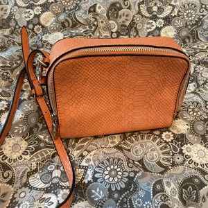 Rosa väska i fakeskinn - Liten men rymlig väska i fakeskinn. Knappt använd, nyskick. Har ett långtxelband som är utbytsbart.