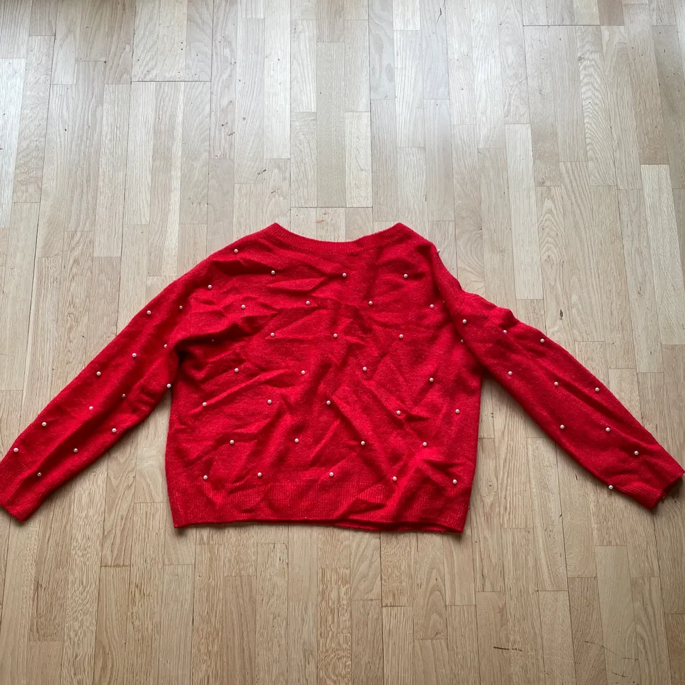 En röd stickad tröja med pärlor på i storlek S ifrån HM. Sitter lite lösare. Fler bilder kan fås och kan skicka! Längd: 53 cm. Stickat.