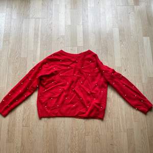En röd stickad tröja med pärlor på i storlek S ifrån HM. Sitter lite lösare. Fler bilder kan fås och kan skicka! Längd: 53 cm