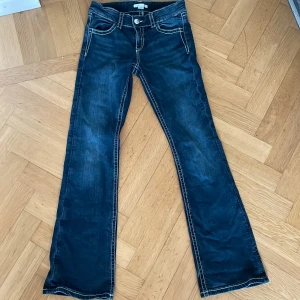 Blå bootcut jeans Gina Tricot 158 - Mörkblå jeans från Gina Tricot i bootcut-modell med snygga broderade detaljer på bakfickorna. Klassisk femficksdesign, kontrastsömmar och låg midja. Perfekta för dig som gillar en retroinspirerad look med lite extra edge. 