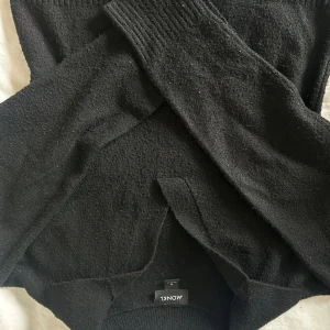 Svart stickad tröja från Monki - En svart stickad tröja från Monki i storlek S. Tröjan har långärmade ärmar med ribbade muddar och en klassisk rund halsringning. Perfekt för lager-på-lager och chill dagar. Enkel och stilren design som funkar till det mesta.