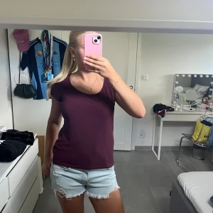 Vinröd t-shirt från H&M - En basic vinröd t-shirt från H&M med rund halsringning och korta ärmar. Modellen är figurnära och enkel, perfekt att matcha med jeans eller shorts. Tillverkad i mjuk bomull som känns skön mot huden.