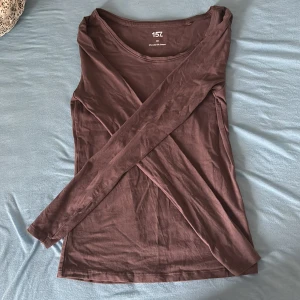 Brun långärmad topp från 157 XS - En basic brun långärmad topp från lager 157 i storlek XS. Tillverkad i mjuk bomull med lite stretch för en skön passform. Enkel design med rund halsringning, perfekt att styla med jeans eller kjol.