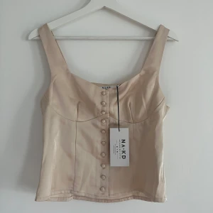 Ny Topp  - Supersnygg champagnefärgad topp från NA-KD i glansig satin. Ny med prislappen kvar och helt oanvänd. 