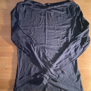 Svart långärmad bomullströja - En enkel svart långärmad tröja i mjuk bomull. Tröjan har en klassisk passform och rund halsringning, perfekt att matcha med jeans eller kjol. Stilren och basic design som funkar till många olika outfits.