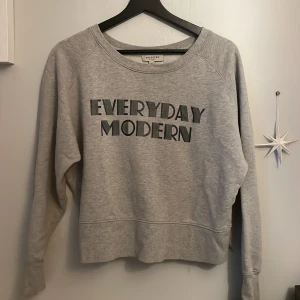Grå sweatshirt från Selected Femme - Grå sweatshirt med trycket 'EVERYDAY MODERN' framtill från Selected Femme. Tröjan har rund halsringning och långa ärmar, rätt kort!