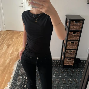 Svart ärmlös topp i bomull - En stilren svart topp med rund hals och ärmlös design.