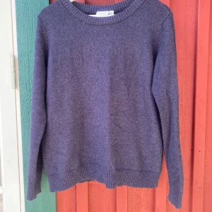 Mörkblå stickad tröja från VILA - En enkel och stilren mörkblå stickad tröja från VILA. Tröjan har rund halsringning, långa ärmar och ribbade muddar vid ärmslut och nederkant. En liten tråd är dragen (se bild), men inget som påverkar funktionen eller syns mycket vid användning.