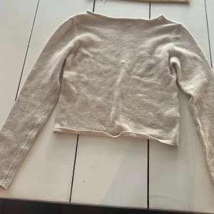 Beige långärmad tröja från Bershka - En stilren beige långärmad tröja från Bershka. Tröjan har en rak, något croppad passform och är tillverkad i ett mjukt, stickat material. Perfekt för lager-på-lager och enkel att matcha med jeans eller kjol.