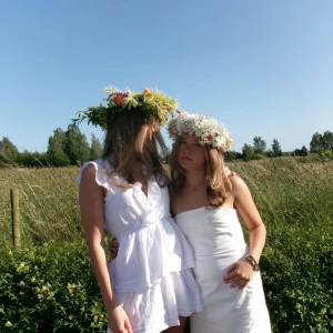 Vit volangklänning med öppen rygg - Supersöt vit kortklänning med volanger och v-ringning. Klänningen har öppen rygg med knytband och är ärmlös med fina detaljer längs kanterna. Använd en gång och inga defekter! 